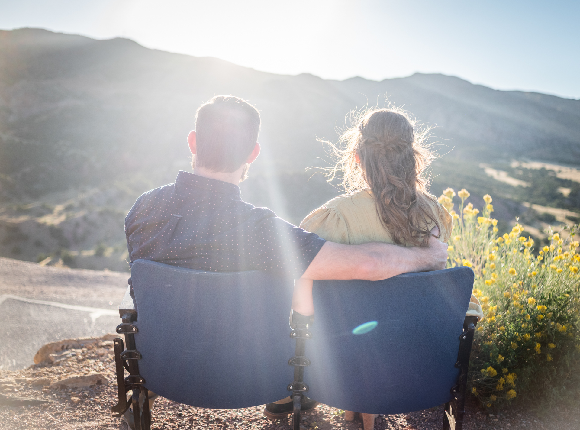 A couple sits together overlooking the Colorado mountains at sunset